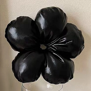 Detailed view of 3D black leather camellia hair tie resting on glass with soft lighting