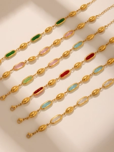 Detail von goldenen Armbändern mit ovalen Glassteinen in Smaragd, Rosa und Blau
