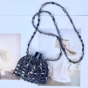 Macro shot of handcrafted black metallic beaded mini bag with a woven fan-shaped pattern
