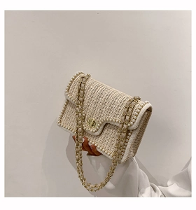 Detail of straw woven bag with pearl trim and golden metal turn-lock closure