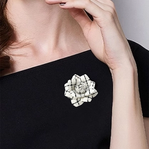 Close-up of vintage black houndstooth camellia flower brooch pinned on model's black top