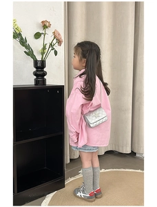 Silver quilted crossbody bag with star decor and chain strap worn by a young girl