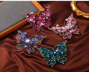 Macro shot of luxury butterfly brooches with colorful rhinestones on silk fabric