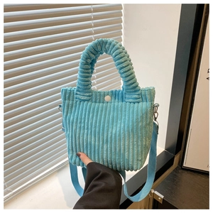 Detail of light blue corduroy bucket bag with pleated handle and white button closure