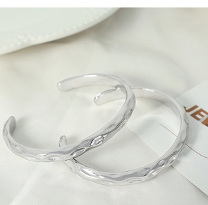 Detailed macro view of silver open bangles featuring irregular hammered metal textures