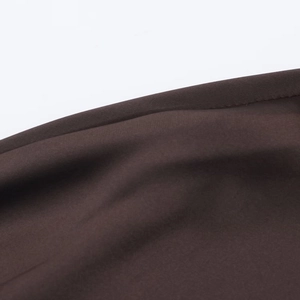 Macro del tessuto di raso marrone scuro che mostra la trama fine e i drappeggi eleganti