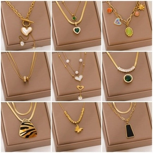 Collage of nine gold necklaces with heart, butterfly and emerald pendants in gift boxes