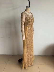 Détails de paillettes dorées et broderies florales sur les manches de la robe de soirée