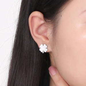 Close-up of minimalist silver clover stud earrings worn by a model in a lifestyle shot