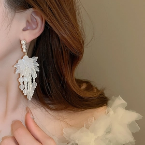 Primo piano di orecchini a fiore in acrilico con nappe di perle finte su una modella