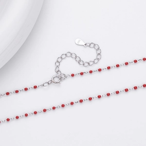 Macro detail of S925 sterling silver chain with red beads and lobster clasp closure