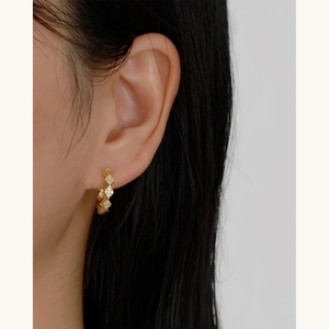 Gold geometric rhombic earrings with embedded cubic zirconia on a female model