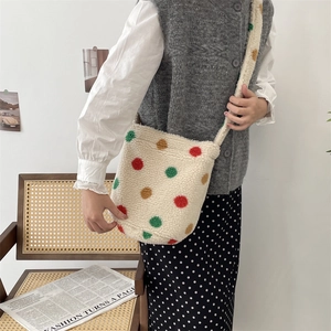 Detail of plush off-white shoulder bag with colorful polka dots on a rattan chair