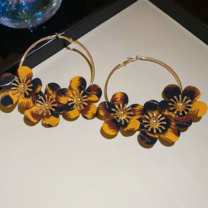 Close-up of golden hoop earrings featuring leopard print fabric flowers and texture