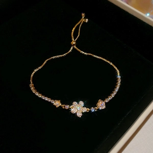 Detail of adjustable gold flower bracelet with sparkling zircons on black velvet case
