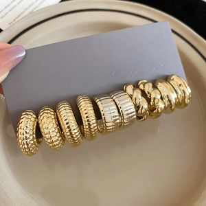 Detail of assorted gold and silver hoop earrings with hammered and braided textures