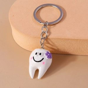 Dettaglio macro di portachiavi a forma di dente con faccina sorridente e fiore viola