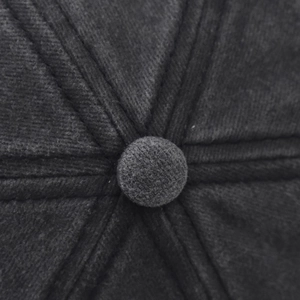 Détail macro du bouton supérieur et des coutures renforcées d'une casquette délavée