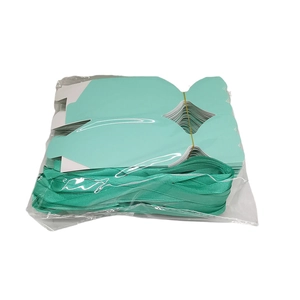 Flat-lay detail of DIY mint green candy boxes with ribbons in transparent packaging