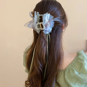 Detail of butterfly hair claw with pearls and long green ribbons on a model back view