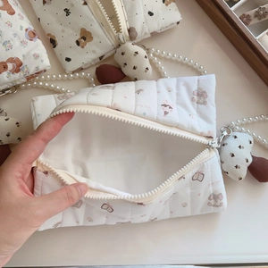 Detail of quilted cosmetic bag showing open zipper compartment with pearl handle