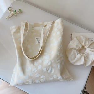 Detail of cream floral jacquard tote bag with matching scrunchie and gold metal hair claw