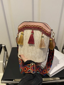 Detail of woven straw bucket bag with pink leather trim and geometric pattern strap