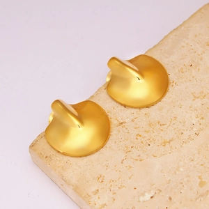 Close-up of golden irregular ripple earrings on a textured stone display pedestal