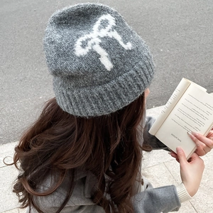 Detail view of grey mohair knit hat featuring white bow pattern and ribbed cuff