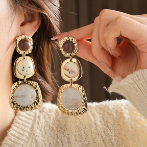 Vintage style geometric resin earrings with gold metal frame worn by a female model