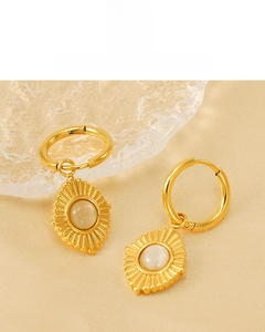 Détail de boucles d'oreilles plaquées or 18K avec motif soleil et pierre œil de chat