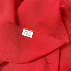 Detailed macro view of 100% silk-feeling red polyester fabric texture and woven label