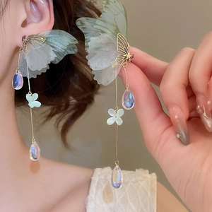 Macro view of butterfly tassel earrings with light green mesh wings and teardrop beads