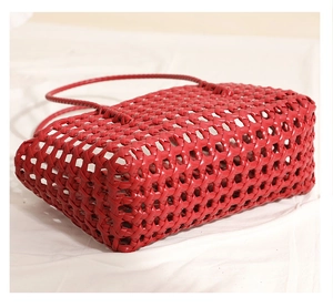 Close-up of red hollow woven shoulder bag side view showing textured plastic material