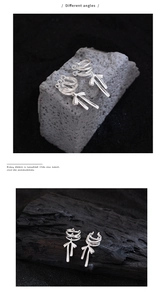 Close-up of silver ribbon bow ear cuffs shown from two angles on artistic background
