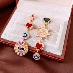 Asymmetric gold dangle earrings with evil eye, hamsa hand symbols and colorful zircons