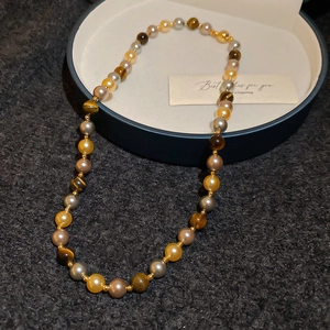 Collier en œil de tigre et perles sur un écrin bleu sur un tissu texturé foncé