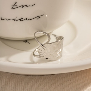 Modern silver textured ring with hammered metal surface shown on white ceramic saucer