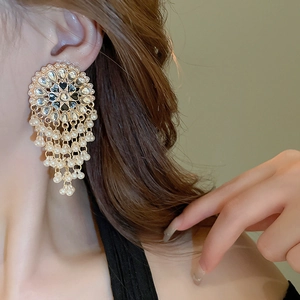 Detail shot of vintage hollow teardrop tassel earrings with pearls on a female model
