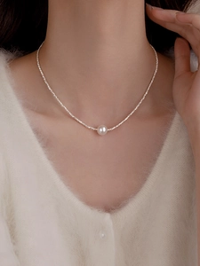 Detail of silver irregular beads and white pearl necklace on woman's neck