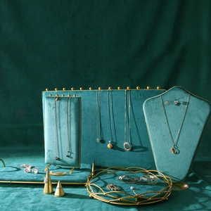 Detail of luxury emerald green velvet jewelry display set with gold metal frames