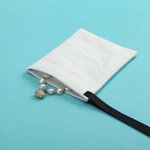 Sacchetto per gioielli in cotone bianco con cordoncino nero e bracciale di perle