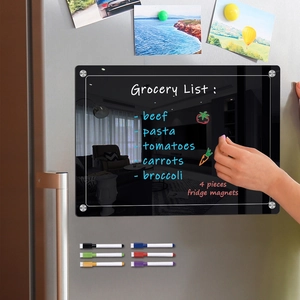Close-up of magnetic acrylic fridge calendar with colorful markers and memo magnets