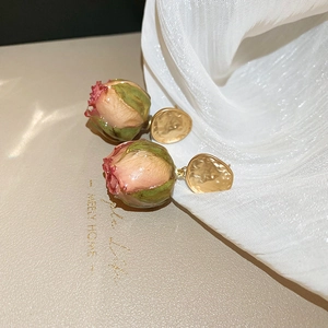 Detailed close-up of real dried rose bud earrings with golden hammered metal texture