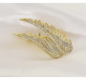 Detailed view of angel wing brooch with gold plating and sparkling white zircons