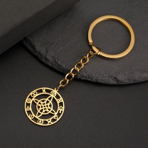 Close-up of gold stainless steel keychain with witch knot pendant on stone background
