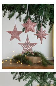 Pink glitter star ornaments hanging on a Christmas tree with warm holiday lights