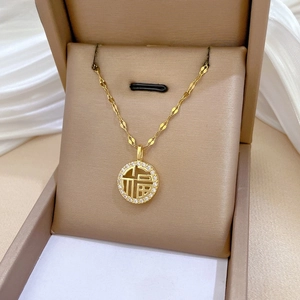 Detailed macro view of gold-plated Fu character pendant with crystal pavé and chain