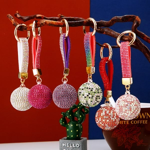 Glittering rhinestone ball keychains in multiple colors hanging on a decorative branch
