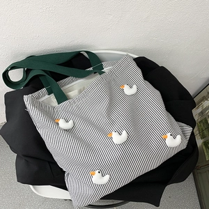 Detail of striped canvas tote bag featuring cute 3D duck accessories and green handle